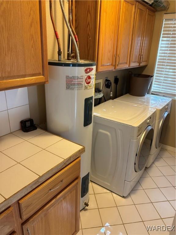 laundry area featuring light tile patterned floors, cabinet space, separate washer and dryer, and electric water heater