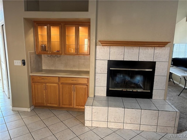 interior space featuring light tile patterned flooring, a tiled fireplace, and baseboards