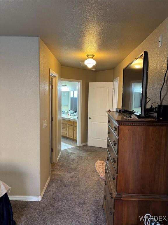 corridor with baseboards, dark carpet, and a textured ceiling