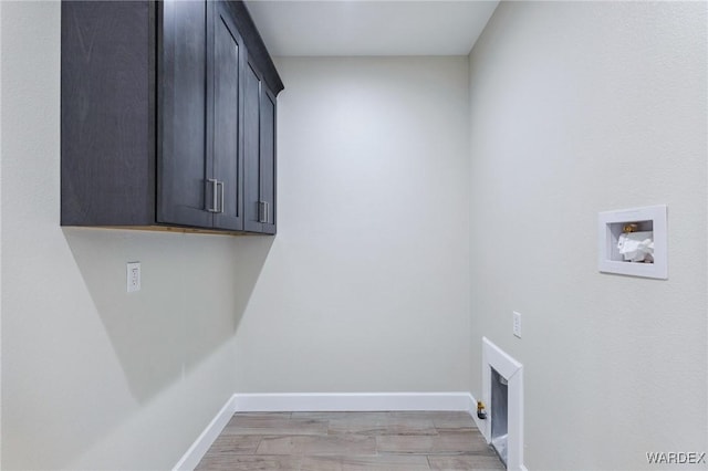 clothes washing area featuring washer hookup, cabinet space, and baseboards