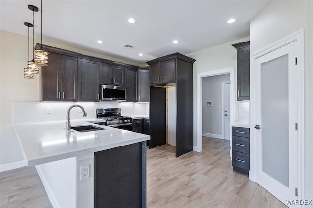 kitchen with dark brown cabinetry, visible vents, stainless steel appliances, light countertops, and a sink