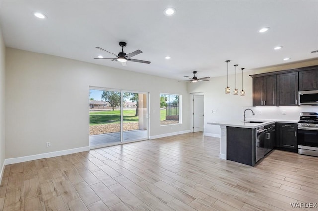 kitchen with appliances with stainless steel finishes, open floor plan, a peninsula, hanging light fixtures, and light countertops