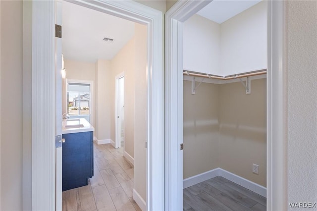 hall with light wood finished floors, a sink, and baseboards