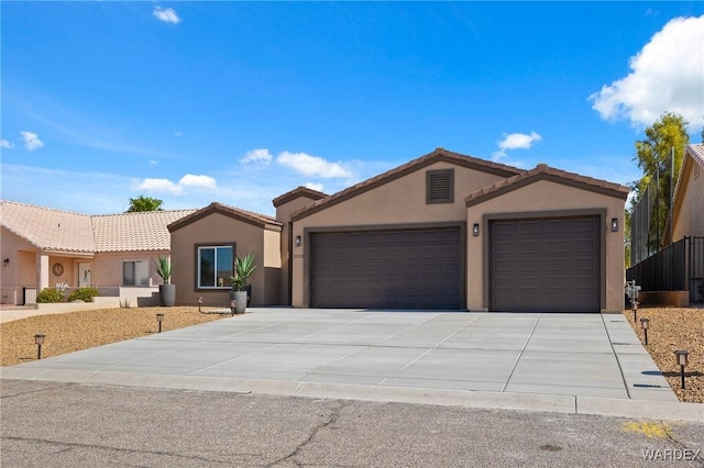 view of front of house with a garage, a tile roof, driveway, and stucco siding