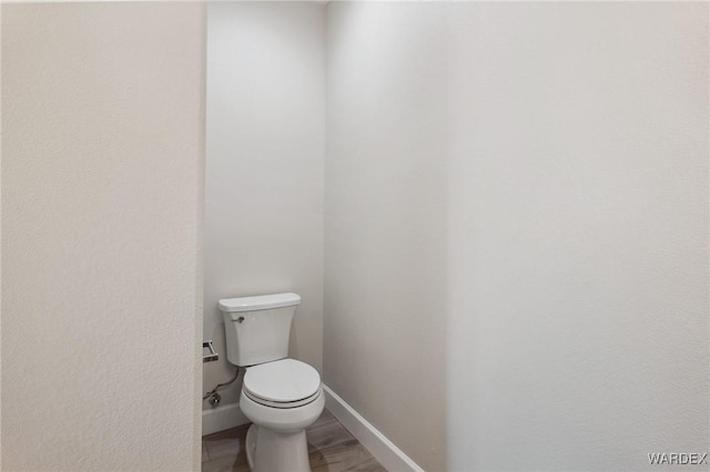 bathroom with wood finished floors, toilet, and baseboards