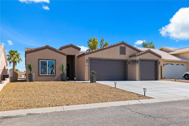 view of front of house featuring a garage, concrete driveway, a tiled roof, and stucco siding