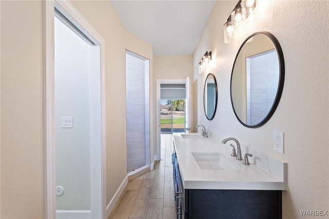 bathroom featuring wood finished floors, a sink, baseboards, and double vanity