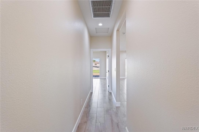 corridor with light wood-type flooring, baseboards, and visible vents