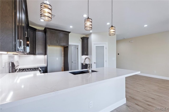 kitchen with light countertops, hanging light fixtures, a sink, and range