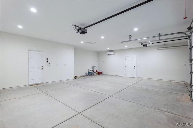 garage with recessed lighting, an AC wall unit, and a garage door opener