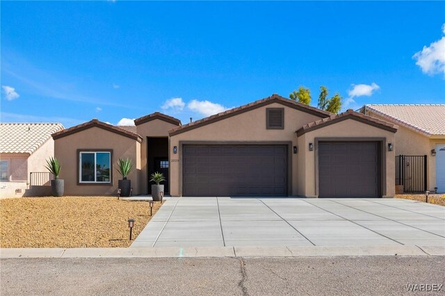 view of front of home featuring a garage, a tile roof, concrete driveway, and stucco siding