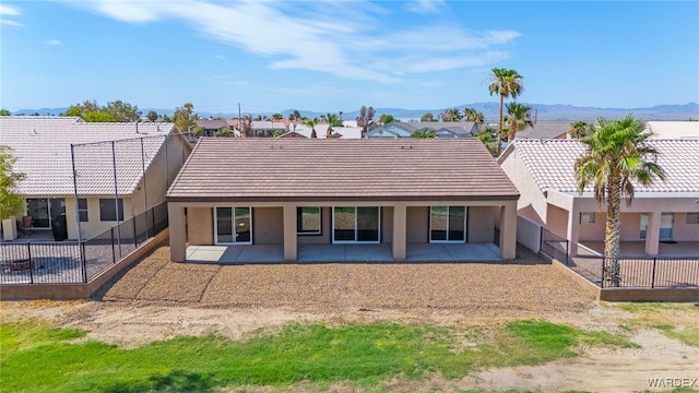 back of house featuring a patio, a tile roof, a residential view, fence, and stucco siding