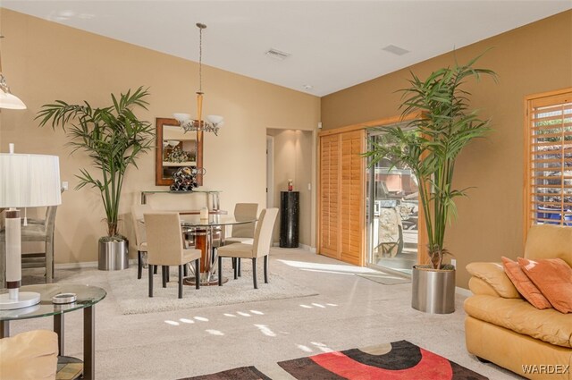 dining room featuring light colored carpet, visible vents, vaulted ceiling, a chandelier, and baseboards