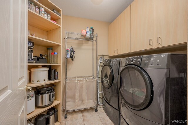 clothes washing area with cabinet space, light tile patterned floors, and independent washer and dryer