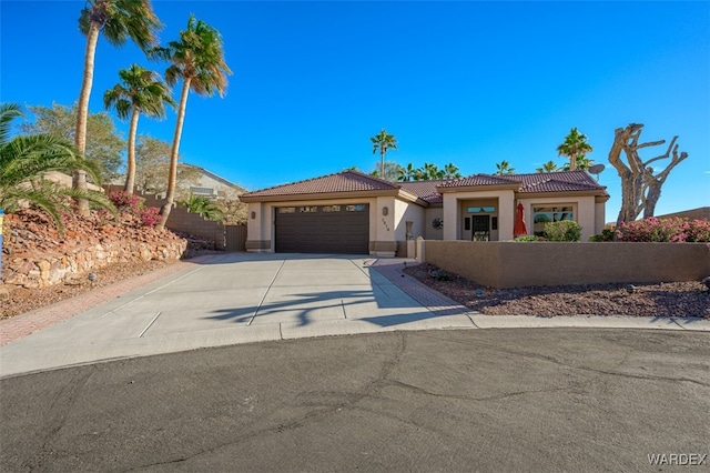 mediterranean / spanish-style home with a fenced front yard, an attached garage, concrete driveway, a tiled roof, and stucco siding