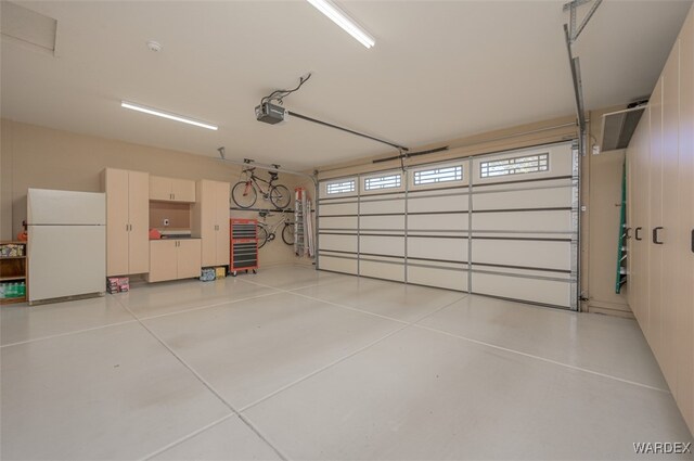 garage featuring a garage door opener and freestanding refrigerator