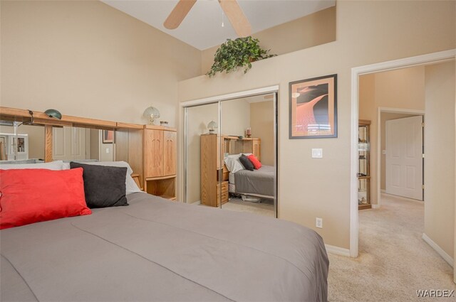 bedroom with ceiling fan, high vaulted ceiling, light carpet, baseboards, and a closet