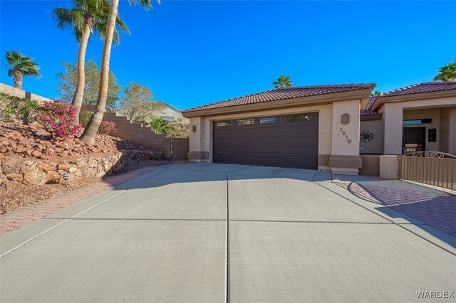 view of front of property featuring driveway, an attached garage, a tiled roof, and stucco siding