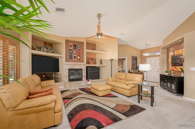 living area with a tile fireplace, light colored carpet, visible vents, built in features, and vaulted ceiling