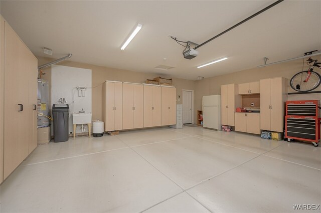 garage featuring a garage door opener, freestanding refrigerator, and a sink