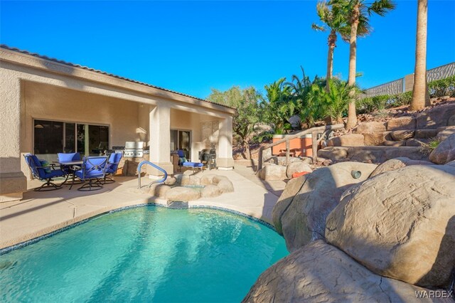 outdoor pool featuring an outdoor kitchen, outdoor dining area, a patio area, and fence