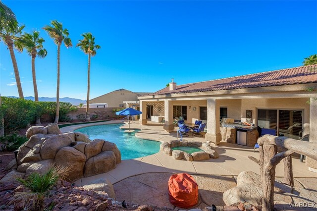 view of pool with a patio, an outdoor kitchen, an in ground hot tub, fence, and a fenced in pool