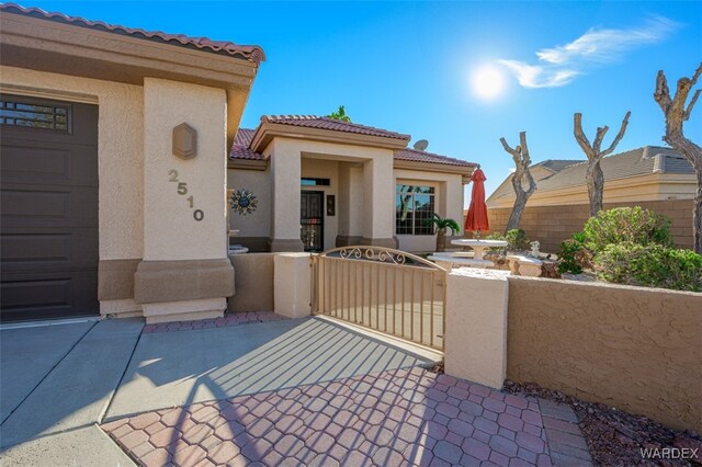 view of front of house featuring a fenced front yard, a tile roof, a gate, and stucco siding