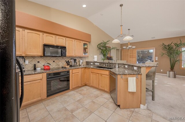 kitchen with glass insert cabinets, dark stone countertops, black appliances, a kitchen bar, and pendant lighting