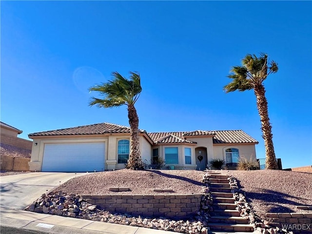 mediterranean / spanish-style home with driveway, an attached garage, a tile roof, and stucco siding