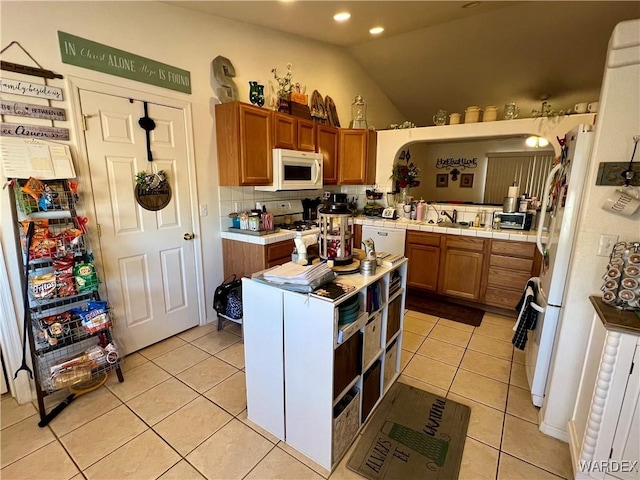 kitchen with tile counters, white appliances, brown cabinets, and light tile patterned floors