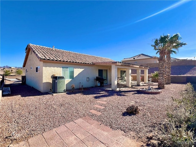 rear view of property with stucco siding, central AC unit, a patio area, fence, and a tiled roof