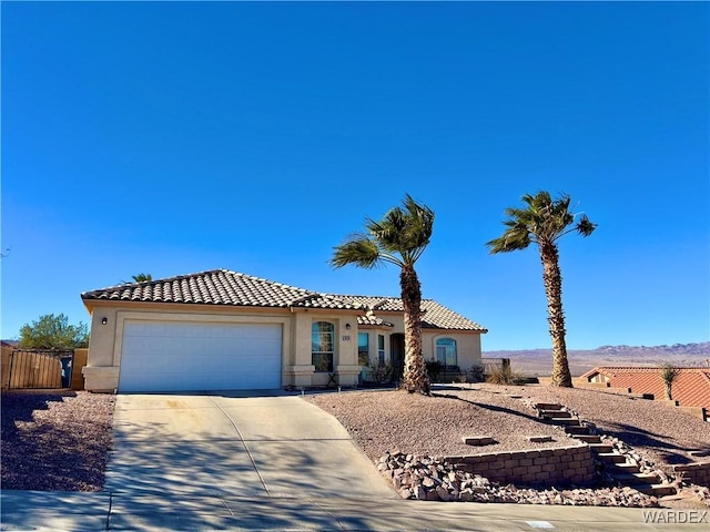 mediterranean / spanish-style house featuring driveway, a tiled roof, an attached garage, and stucco siding