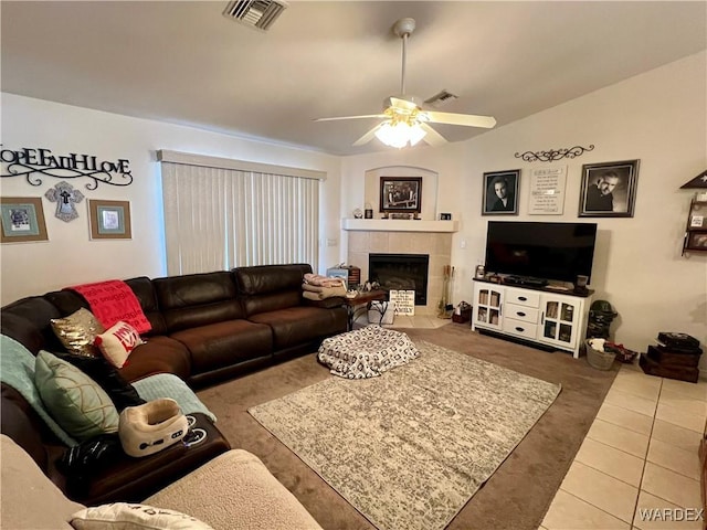 tiled living room featuring lofted ceiling, ceiling fan, a tile fireplace, and visible vents