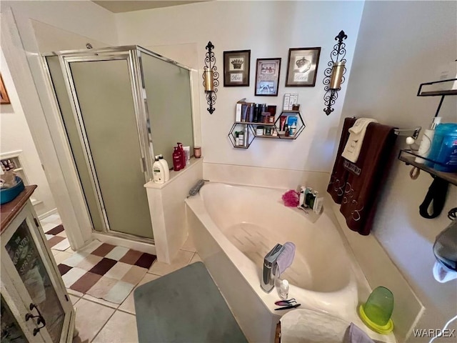 bathroom featuring a stall shower, a bath, and tile patterned floors