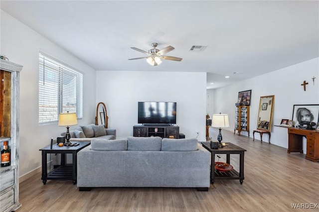 living area featuring a ceiling fan, baseboards, visible vents, and wood finished floors