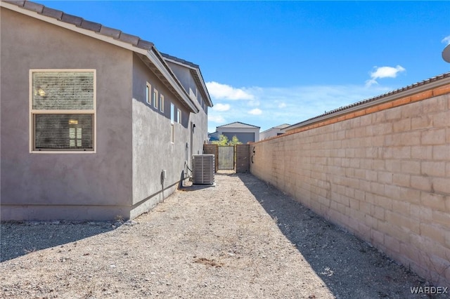 view of side of home featuring central air condition unit, fence, and stucco siding