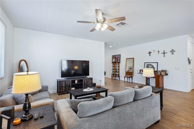 living area with light wood finished floors, baseboards, visible vents, and a ceiling fan