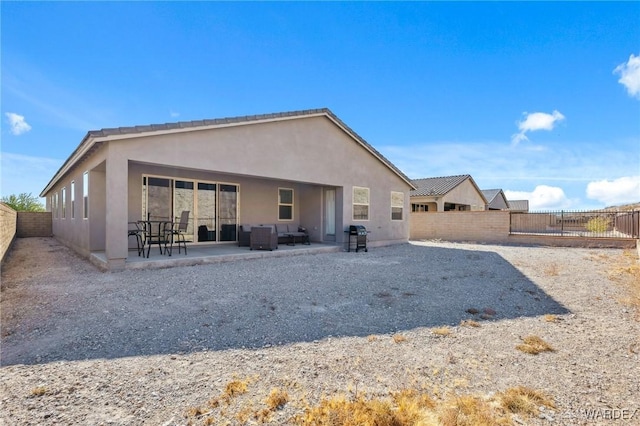 rear view of property featuring a fenced backyard, a patio, and stucco siding