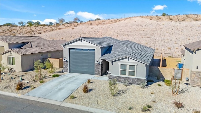 view of front of home with an attached garage, fence, stone siding, driveway, and stucco siding