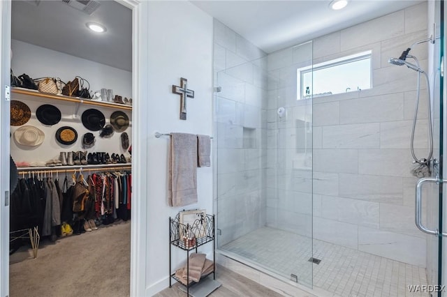 full bath with a spacious closet, visible vents, tiled shower, and recessed lighting