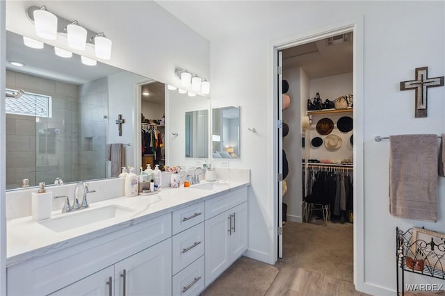 bathroom with double vanity, a shower stall, a walk in closet, and a sink