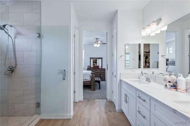 full bath featuring ensuite bathroom, wood finished floors, a sink, a shower stall, and double vanity