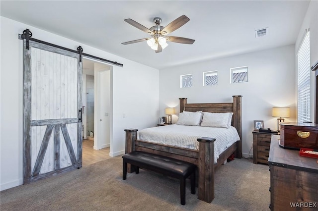 bedroom with light carpet, a barn door, visible vents, baseboards, and a ceiling fan