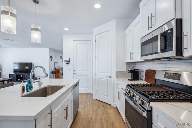 kitchen featuring stainless steel appliances, white cabinetry, hanging light fixtures, and a sink