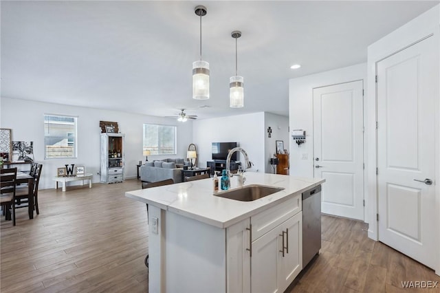 kitchen featuring light countertops, open floor plan, white cabinets, a sink, and an island with sink