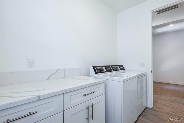 laundry area featuring cabinet space, visible vents, baseboards, light wood-style flooring, and washer and dryer