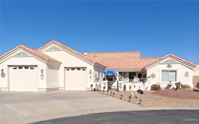 ranch-style home with a garage, concrete driveway, a tile roof, and stucco siding