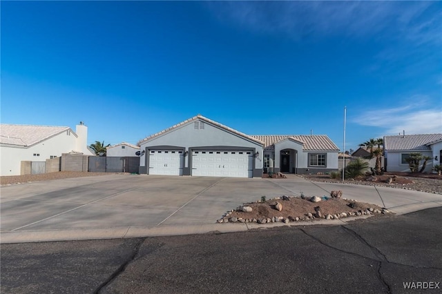 view of front of house featuring an attached garage, fence, concrete driveway, a residential view, and stucco siding