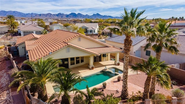 rear view of house with a residential view, a fenced backyard, a patio, and a mountain view