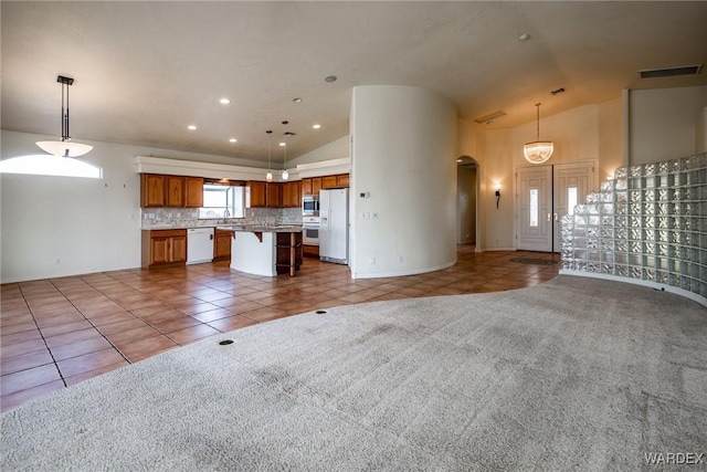 unfurnished living room featuring visible vents, arched walkways, tile patterned floors, carpet floors, and a sink